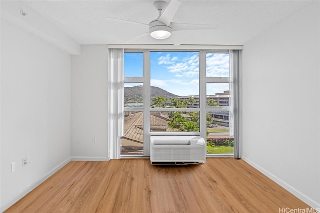 doorway with a wall unit AC, ceiling fan, a textured ceiling, and light wood-type flooring