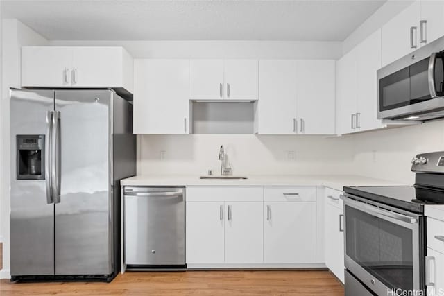 kitchen featuring sink, white cabinets, stainless steel appliances, and light wood-type flooring