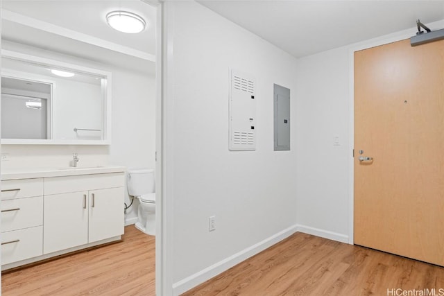 bathroom with hardwood / wood-style floors, vanity, electric panel, and toilet