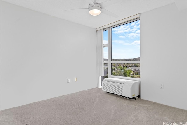 carpeted spare room with a wall unit AC and ceiling fan