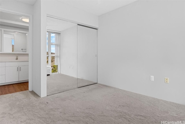 unfurnished bedroom with light carpet, a closet, and sink