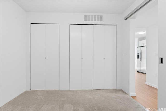 interior space featuring stainless steel fridge, light colored carpet, and two closets