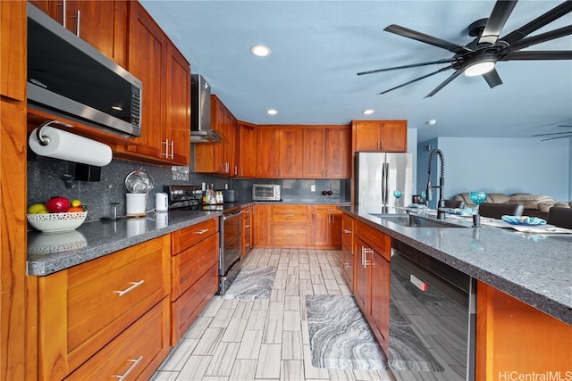 kitchen with decorative backsplash, wall chimney exhaust hood, black appliances, sink, and ceiling fan