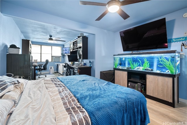 bedroom featuring ceiling fan, cooling unit, and light wood-type flooring