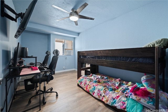 bedroom featuring ceiling fan, cooling unit, and light wood-type flooring