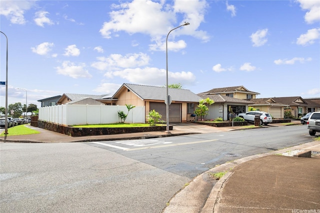 94-1420 Kahuli St, Waipahu, HI 96797 - view of front facade featuring an attached garage, fence, concrete driveway, a residential view, and stucco siding