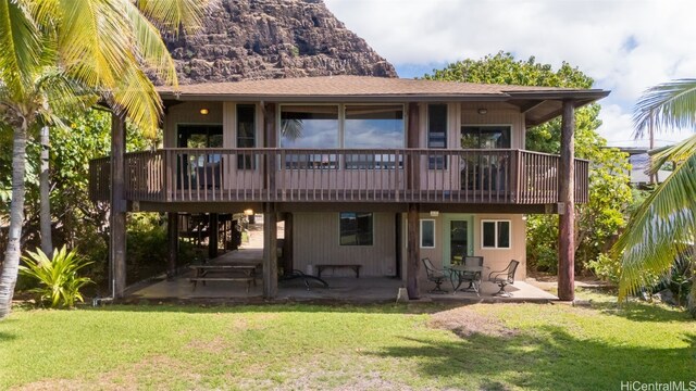 rear view of property with a yard, a deck, and a patio