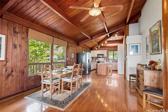 dining space with lofted ceiling with beams, wooden walls, wooden ceiling, and light wood-type flooring