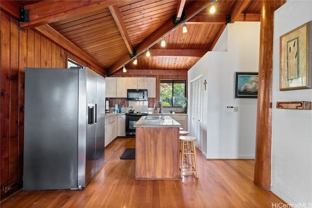 kitchen featuring a breakfast bar area, black appliances, an island with sink, and light wood-type flooring