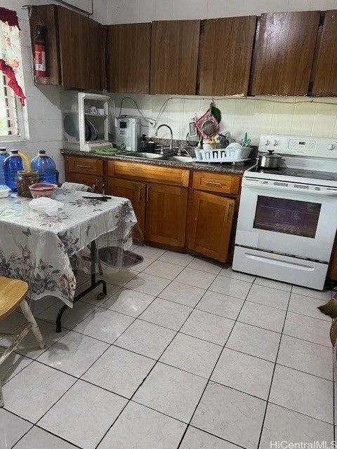 kitchen featuring light tile patterned flooring, sink, electric range, and backsplash