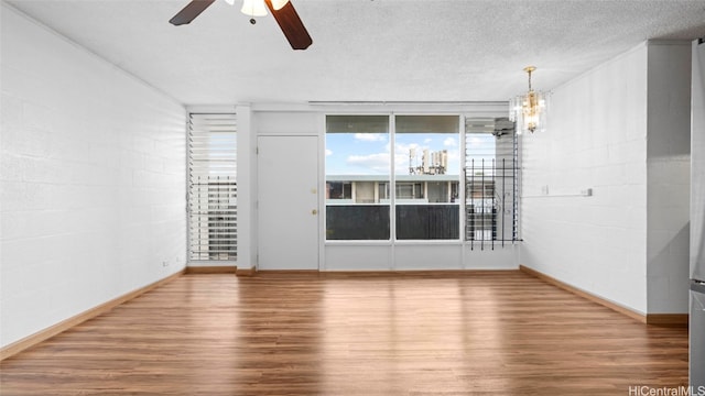 unfurnished room with hardwood / wood-style floors, a textured ceiling, and ceiling fan with notable chandelier