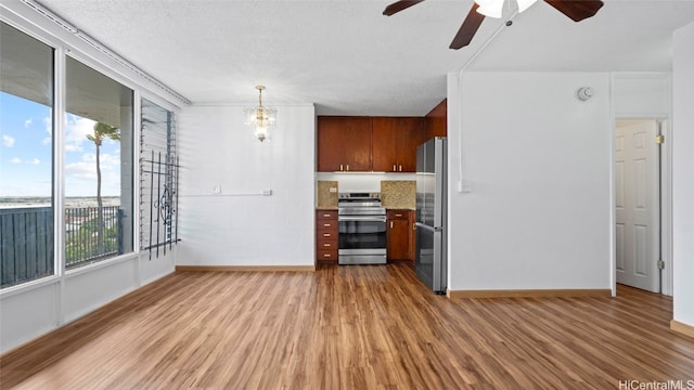 unfurnished living room featuring a textured ceiling, wood-type flooring, and ceiling fan with notable chandelier