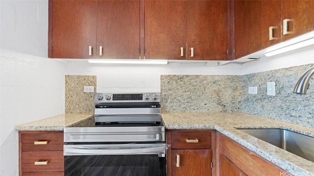 kitchen featuring stainless steel electric stove, decorative backsplash, sink, and light stone counters