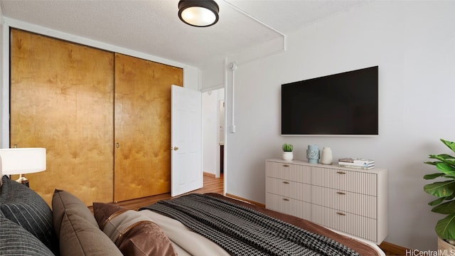 bedroom with light hardwood / wood-style floors, a closet, and a textured ceiling