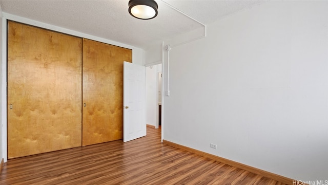 unfurnished bedroom featuring a closet, a textured ceiling, and hardwood / wood-style flooring