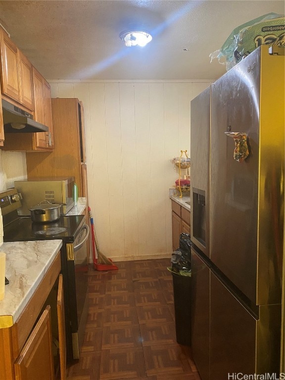 kitchen featuring wooden walls, dark parquet flooring, and stainless steel appliances