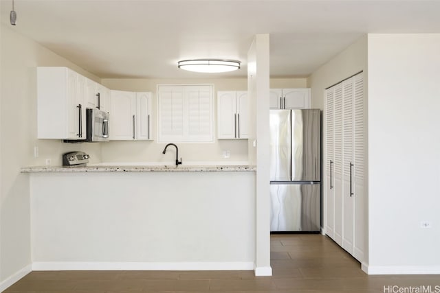 kitchen featuring dark hardwood / wood-style floors, white cabinetry, light stone counters, and appliances with stainless steel finishes