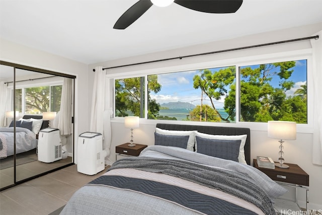 bedroom with ceiling fan, multiple windows, a closet, and a water view