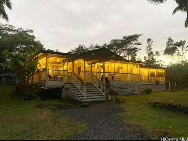 rear view of house featuring a wooden deck and a lawn