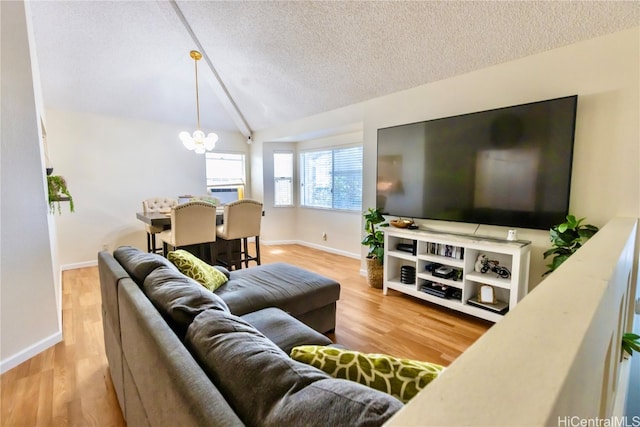 living room with a textured ceiling, vaulted ceiling, a notable chandelier, and light hardwood / wood-style flooring