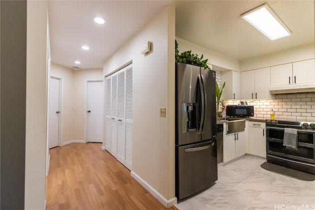 kitchen with white cabinetry, appliances with stainless steel finishes, light hardwood / wood-style floors, and tasteful backsplash