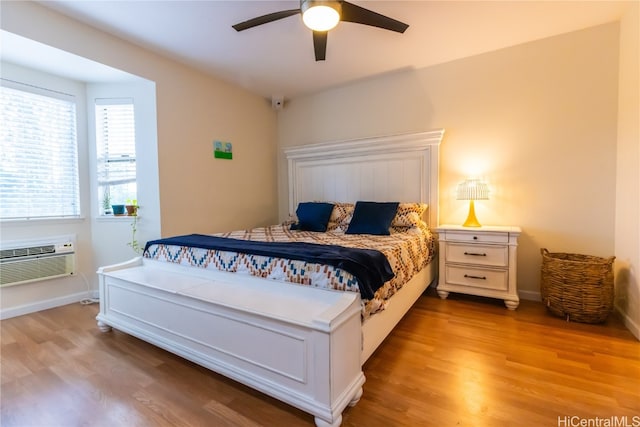 bedroom with ceiling fan, light wood-type flooring, and a wall mounted air conditioner