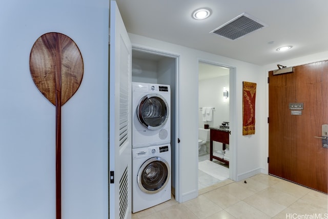 laundry room with stacked washer / dryer and light tile patterned floors