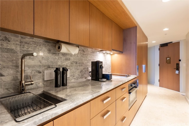 kitchen featuring sink, decorative backsplash, and oven