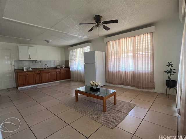 unfurnished living room with a textured ceiling, sink, ceiling fan, and light tile patterned floors