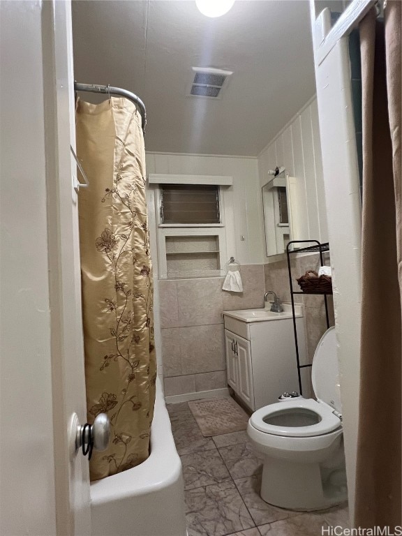 full bathroom with toilet, vanity, shower / bath combo with shower curtain, and tile walls