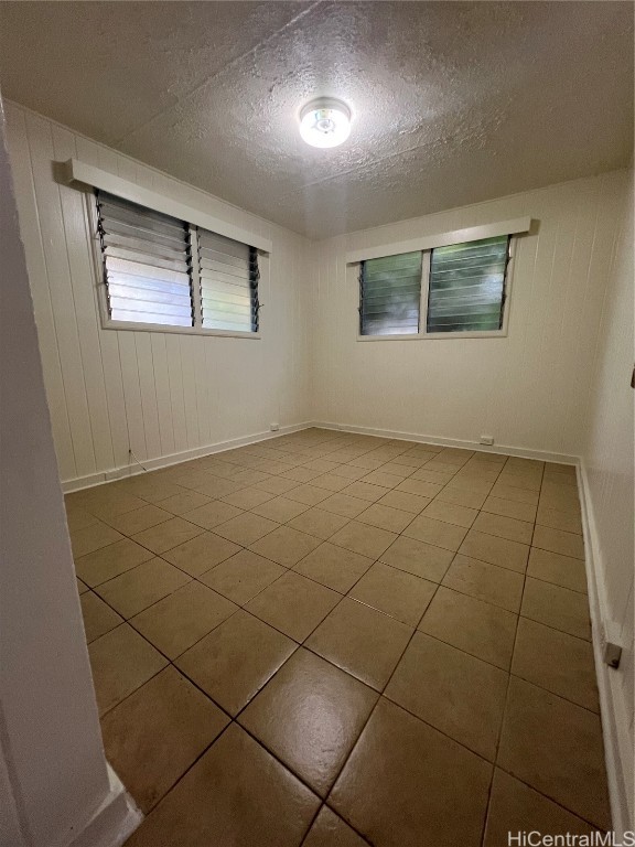 spare room with tile patterned flooring and a textured ceiling