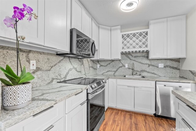 kitchen featuring a sink, white cabinets, wood finished floors, and stainless steel appliances