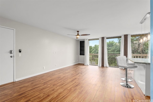 unfurnished living room with baseboards, light wood-style floors, ceiling fan, and floor to ceiling windows