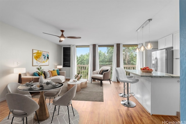 dining room featuring baseboards, ceiling fan, floor to ceiling windows, rail lighting, and light wood-type flooring