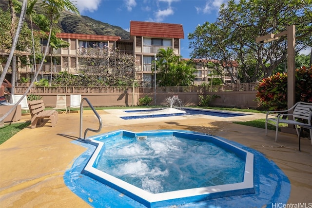 view of pool with a patio area, a hot tub, and fence