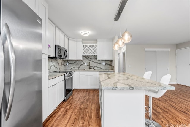 kitchen with a kitchen island, a breakfast bar, a sink, stainless steel appliances, and tasteful backsplash