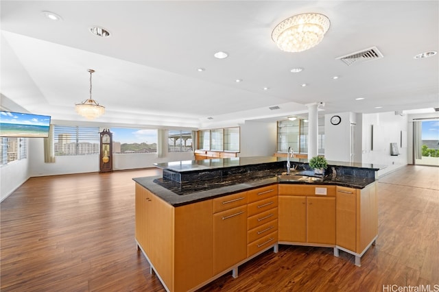 kitchen featuring a spacious island, dark hardwood / wood-style flooring, dark stone counters, and sink