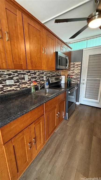 kitchen featuring sink, stainless steel appliances, tasteful backsplash, dark stone countertops, and wood-type flooring