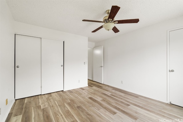 unfurnished bedroom featuring light hardwood / wood-style flooring, a textured ceiling, a closet, and ceiling fan