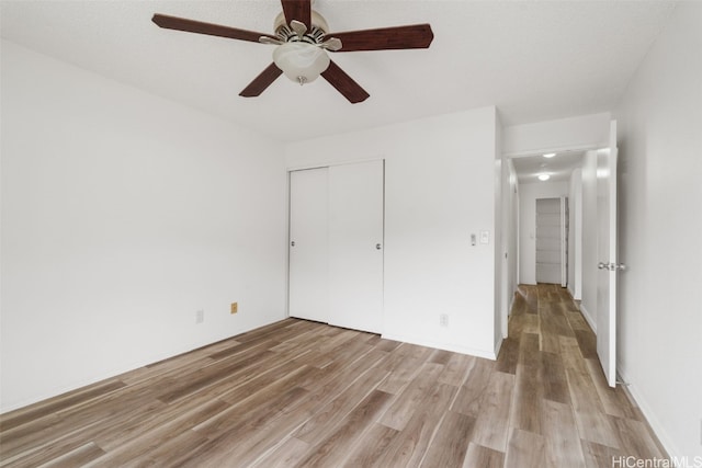 unfurnished bedroom with a closet, light wood-type flooring, and ceiling fan