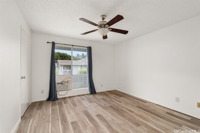 unfurnished room with ceiling fan, a textured ceiling, light hardwood / wood-style flooring, and a wall mounted AC