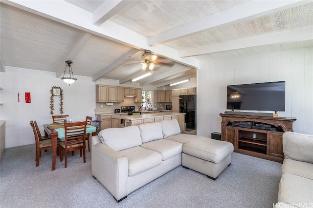 living room featuring wood walls, light carpet, sink, ceiling fan, and vaulted ceiling with beams