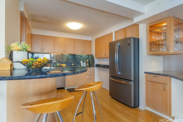 kitchen featuring backsplash, a textured ceiling, light wood-type flooring, and stainless steel refrigerator