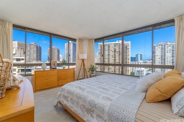 bedroom with expansive windows, light carpet, and a textured ceiling