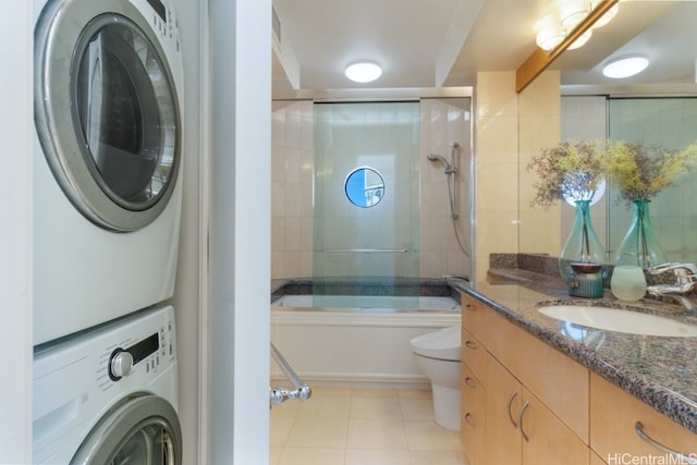 full bathroom featuring vanity, toilet, combined bath / shower with glass door, and stacked washer and clothes dryer