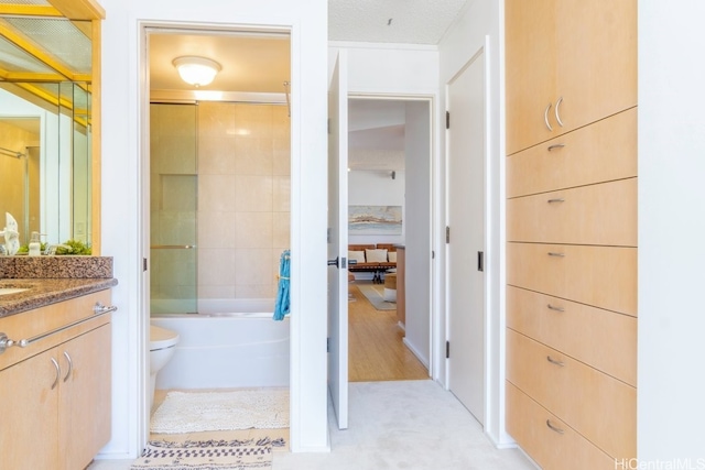 full bathroom featuring toilet, enclosed tub / shower combo, and vanity