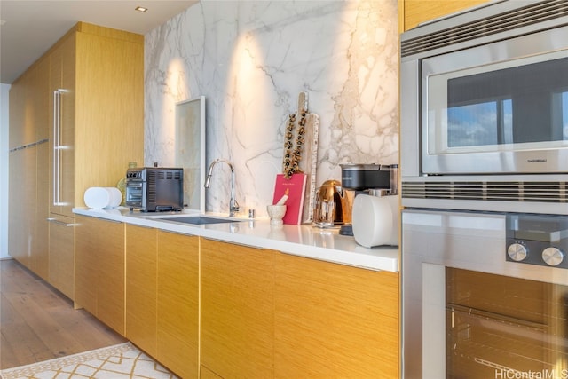 kitchen with stainless steel appliances, sink, and light hardwood / wood-style flooring