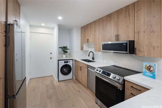 kitchen with sink, stainless steel appliances, decorative backsplash, washer / dryer, and light wood-type flooring