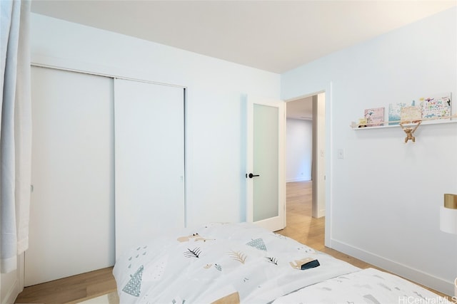 bedroom with light hardwood / wood-style floors and a closet