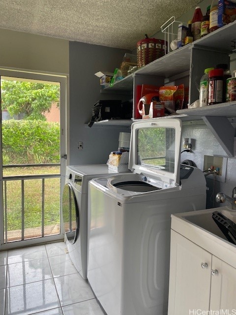 clothes washing area featuring light tile patterned floors, cabinets, plenty of natural light, and washing machine and clothes dryer